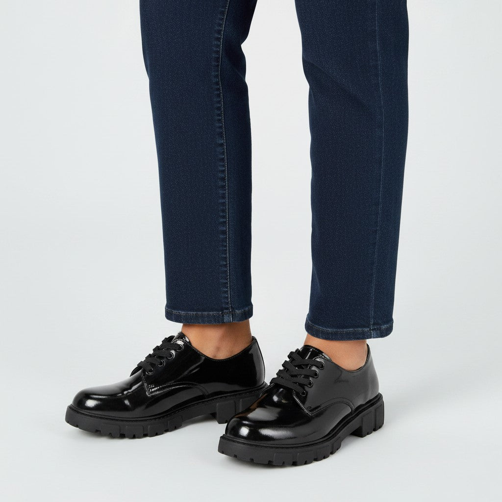 Black patent leather Oxford shoes worn by female model leg shot