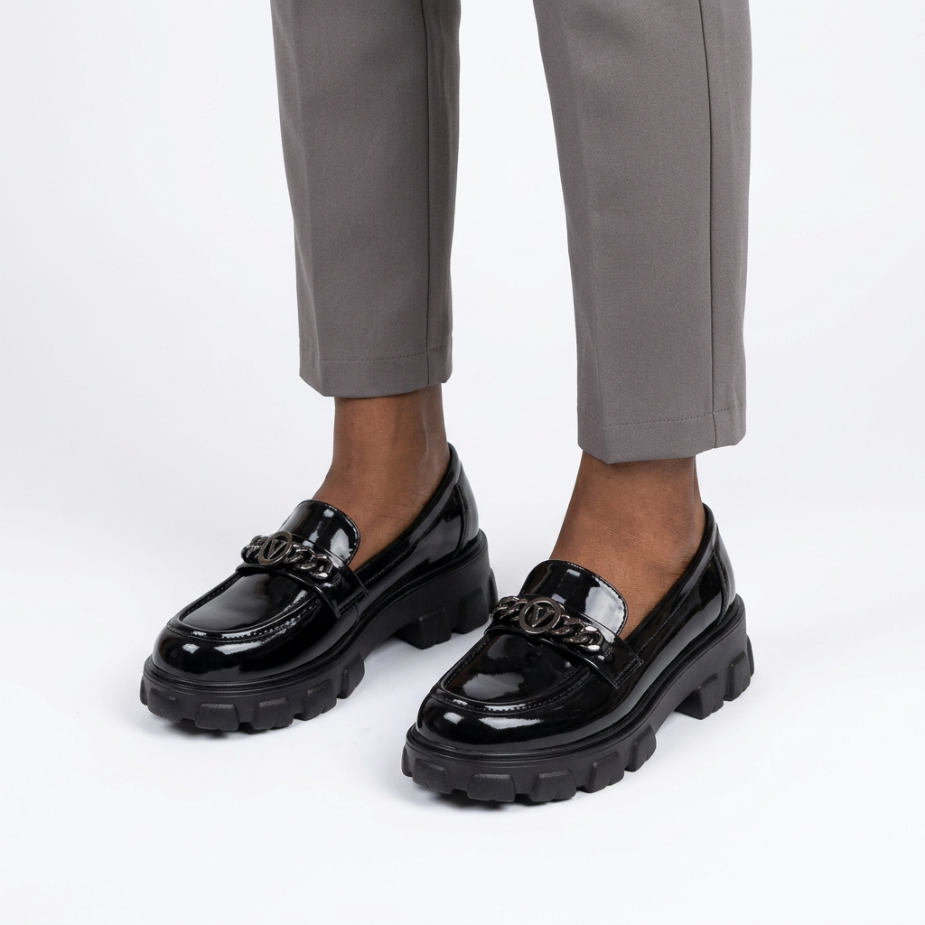 Adult woman wearing black glossy chain-detail chunky loafers