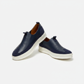 Navy leather slip-on sneakers with white sole, centred on a plain off-white background