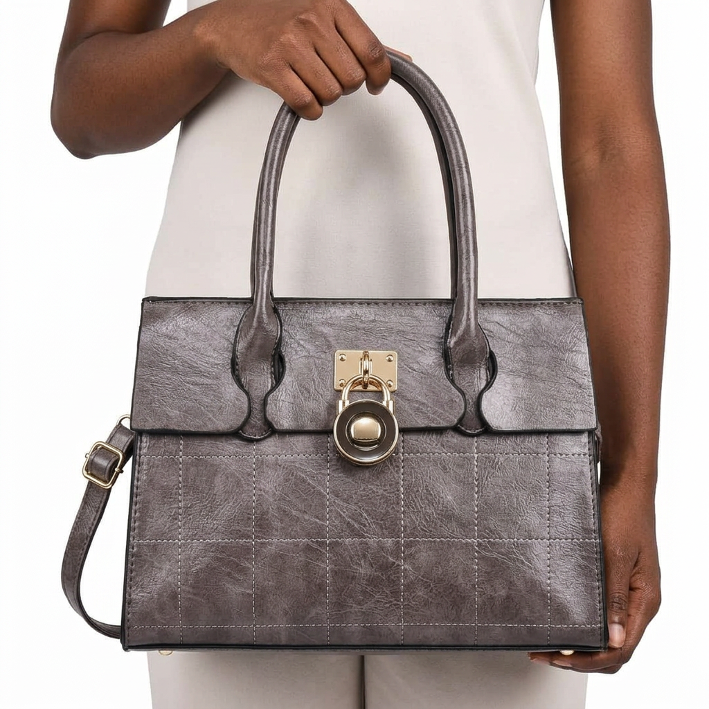 Hand-focused presentation of deep-brown double-handle handbag with stitched panels and circular lock detail