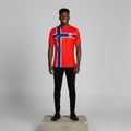 Nigerian male model wearing red Nordic cross graphic football jersey on concrete plinth