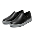 Matching pair of black slip-on shoes with grey soles and side eyelets on white