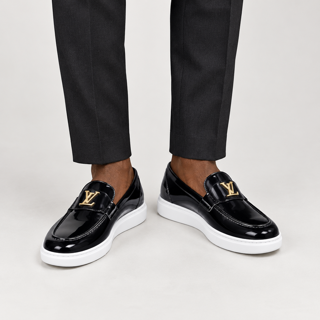 Model wearing black gold-detail slip-on shoes with white soles