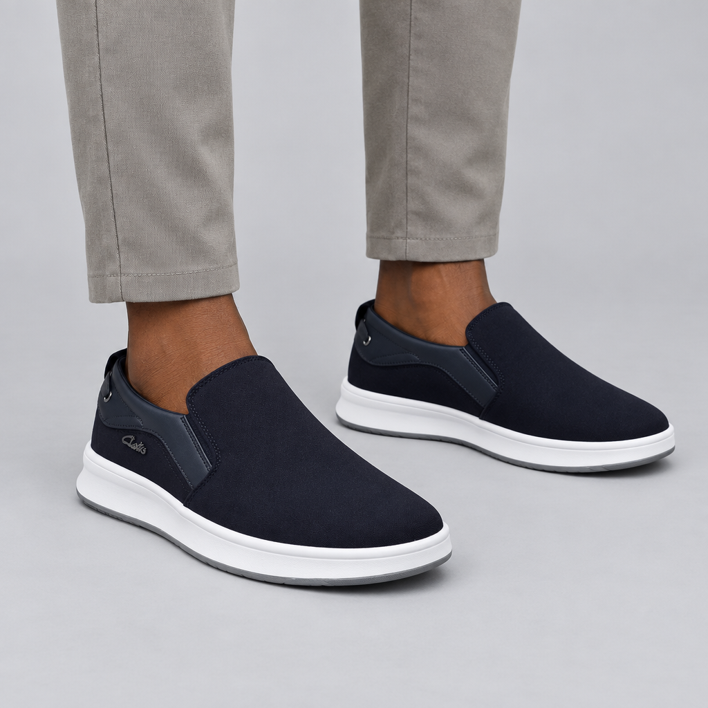 Both dark navy slip-on sneakers worn by a Nigerian man against a plain grey studio background