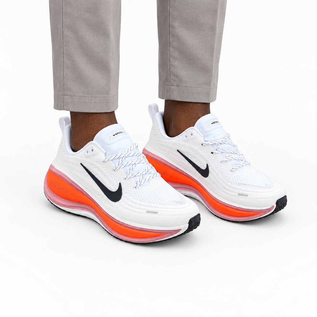 Adult model wearing white lace-up sneakers with orange sole accents