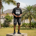 Nigerian male model wearing men's black washed embroidered graphic chain charm denim shorts streetwear style