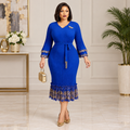 Adult Black woman wearing royal blue gold-trimmed bell sleeve dress