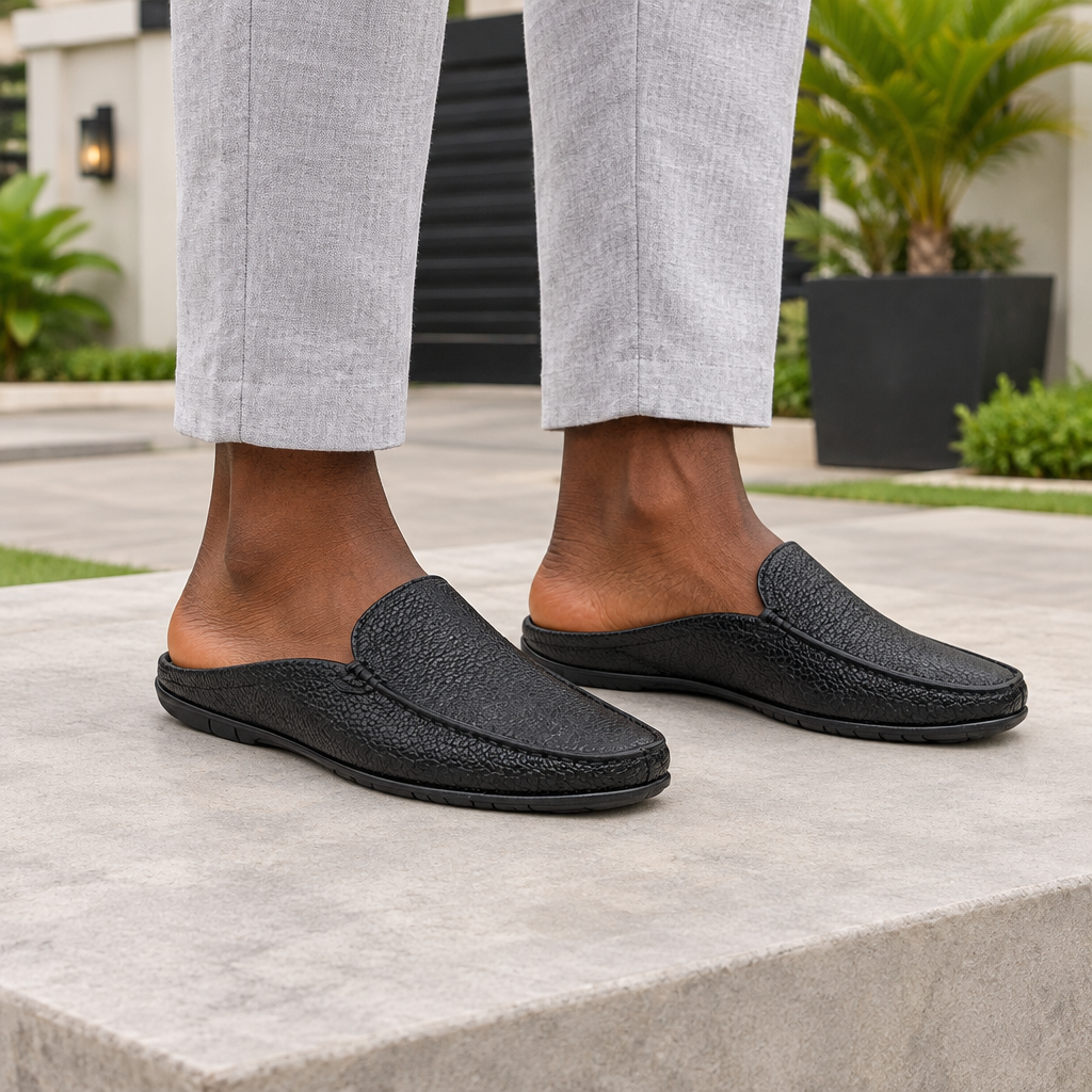 Man wearing black pebble grain backless mule slippers with grey linen trousers