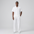 Nigerian male model wearing white tie-neck shirt and wide-leg trouser set