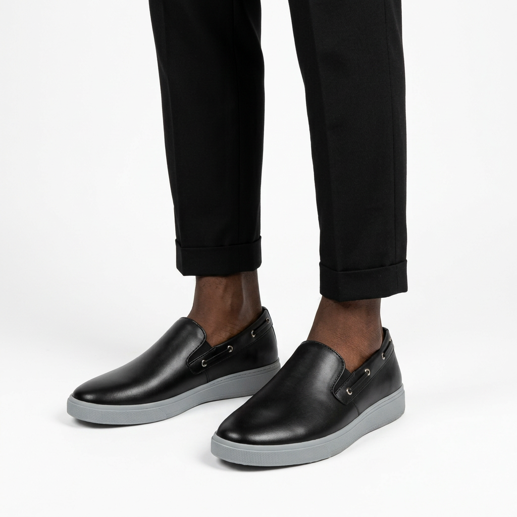 Black slip-on shoes with grey soles worn with black ankle trousers