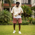 Nigerian male model wearing terracotta bleached graphic distressed sweat shorts — full body streetwear shot