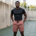 Black Nigerian male model wearing mud red premium sport shorts with black jersey in urban street workout setting