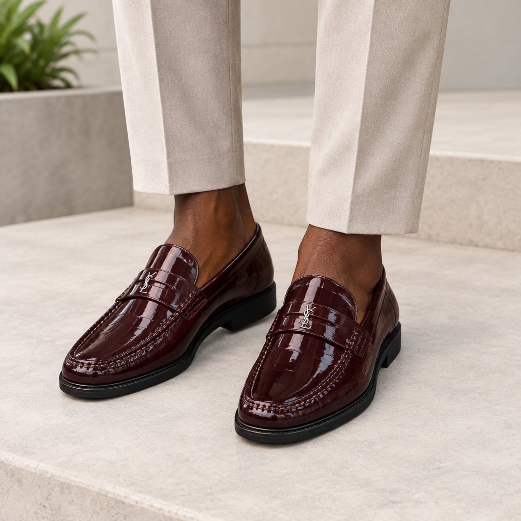 Black model wearing oxblood men's patent loafers with polished metal detail
