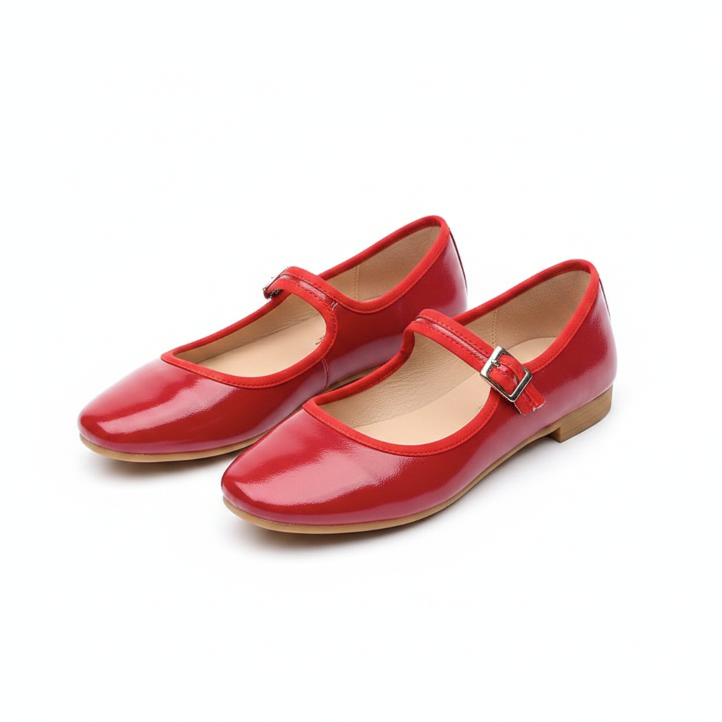Pair of red patent leather Mary Jane flats with ankle strap and silver buckle on white background