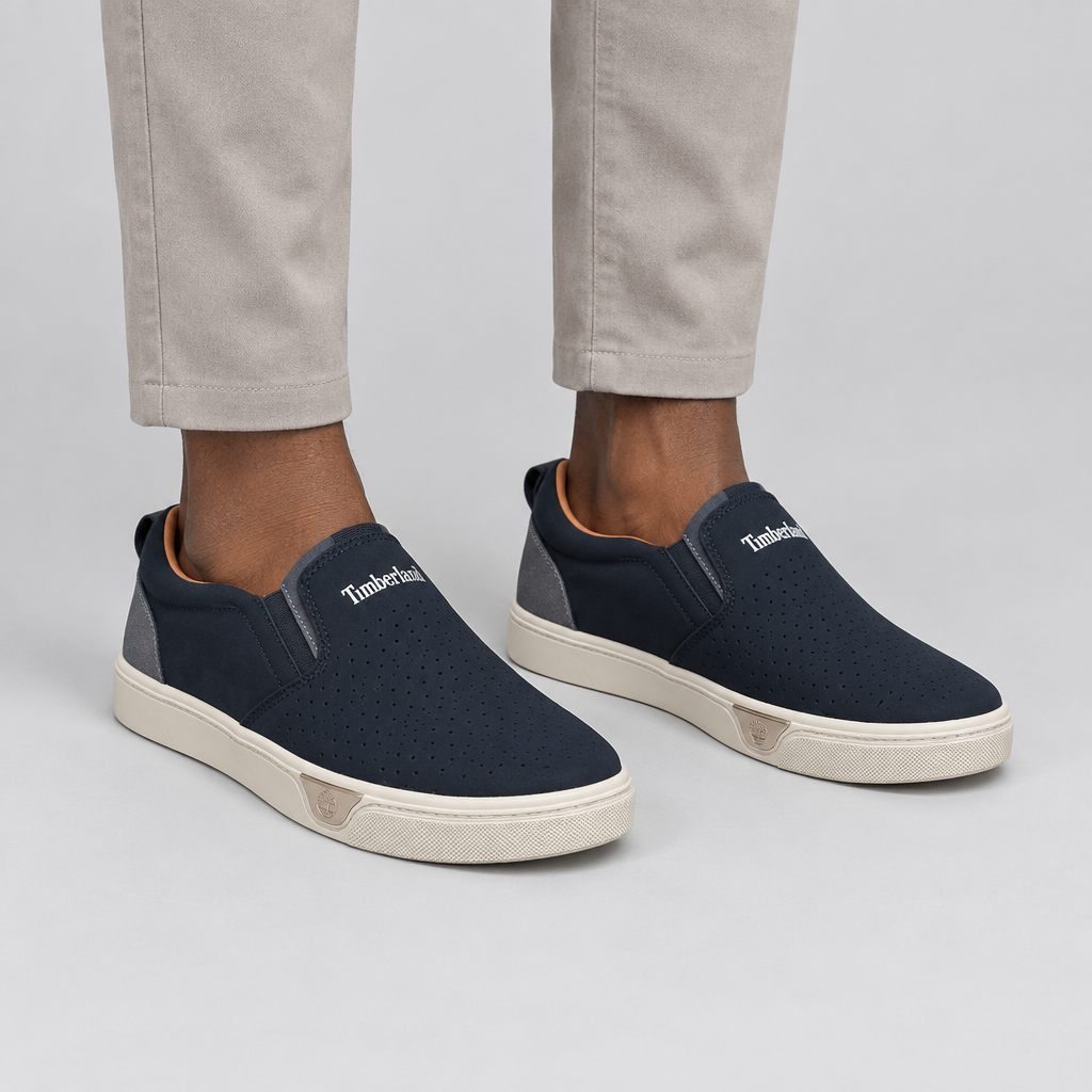 Both navy perforated slip-on sneakers worn against a plain studio background