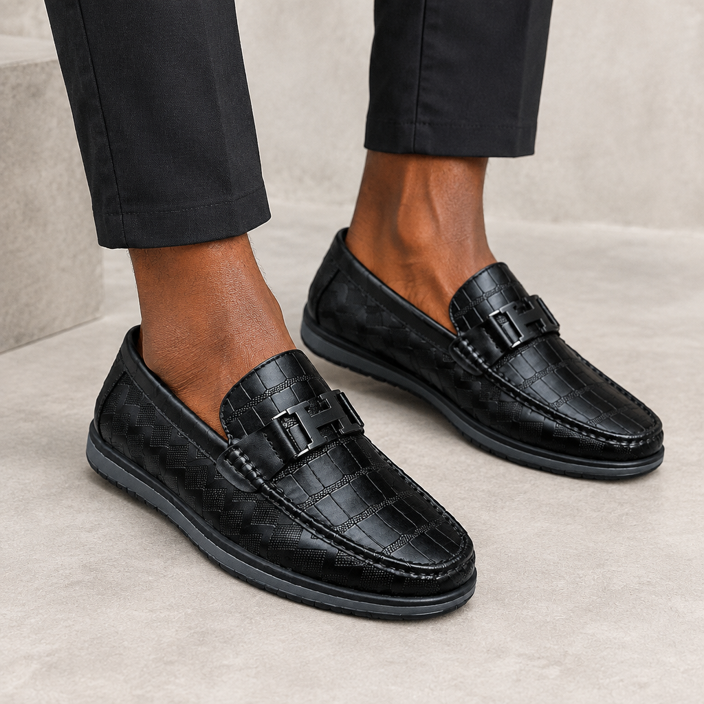 Black textured buckle loafers worn on both feet