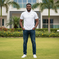 Nigerian male model wearing men's white polo shirt with branded shoulder tape, garden setting