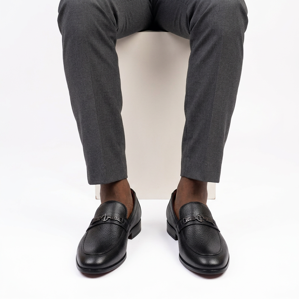 Black textured geometric-detail loafers properly worn on both feet
