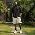 Nigerian male model wearing cream triple stripe fleece drawstring shorts in upscale outdoor setting