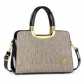 Champagne textured structured handbag with black handles and gold-tone accents on white