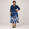 Black Nigerian model wearing a navy pleated gown with floral waist accents and an abstract-print skirt