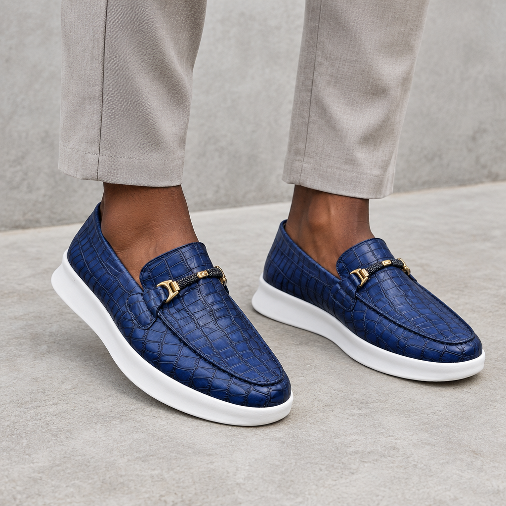 Navy blue embossed loafers with gold-tone hardware, worn on both feet