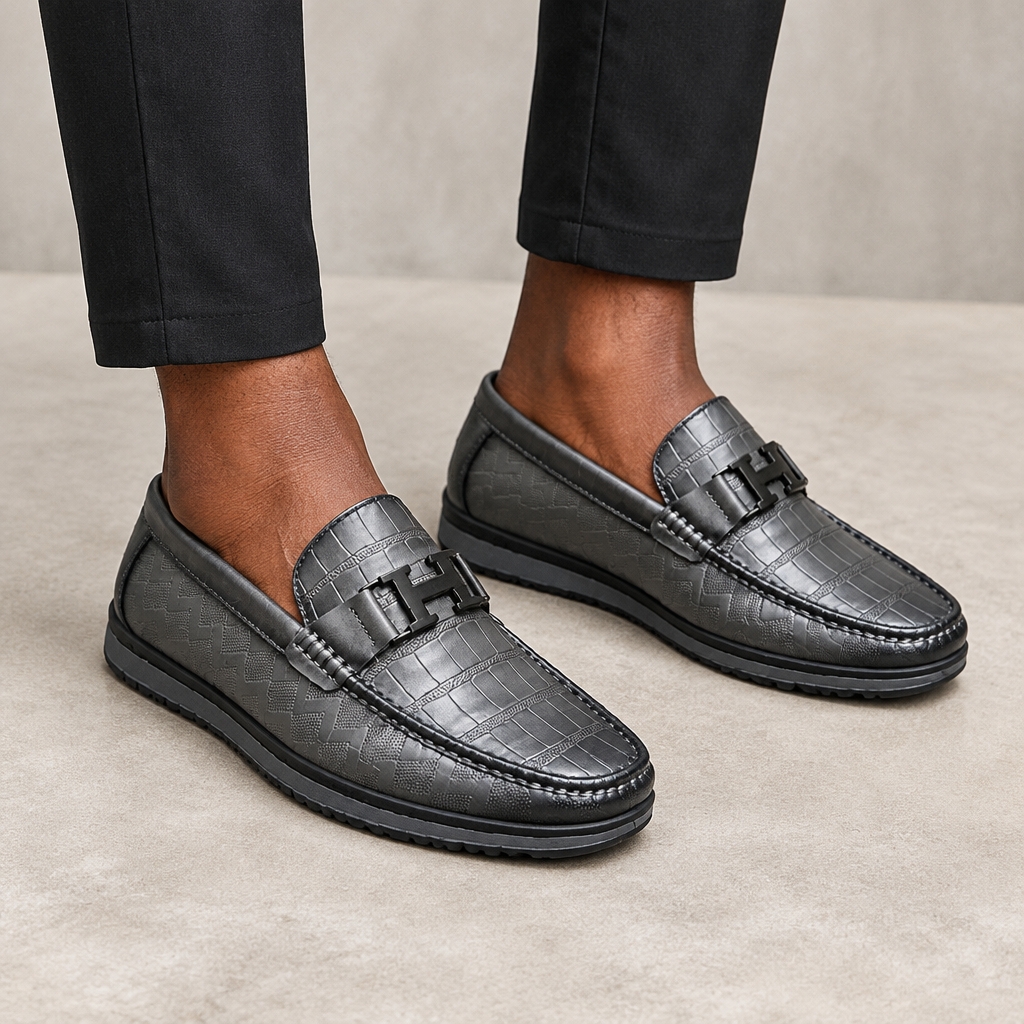 Black patterned buckle loafers worn on both feet