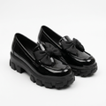 Complete pair of black glossy fabric-bow chunky loafers on white