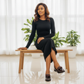 Nigerian female model seated in black midi skirt wearing brown croc-embossed patent loafers with bow detail