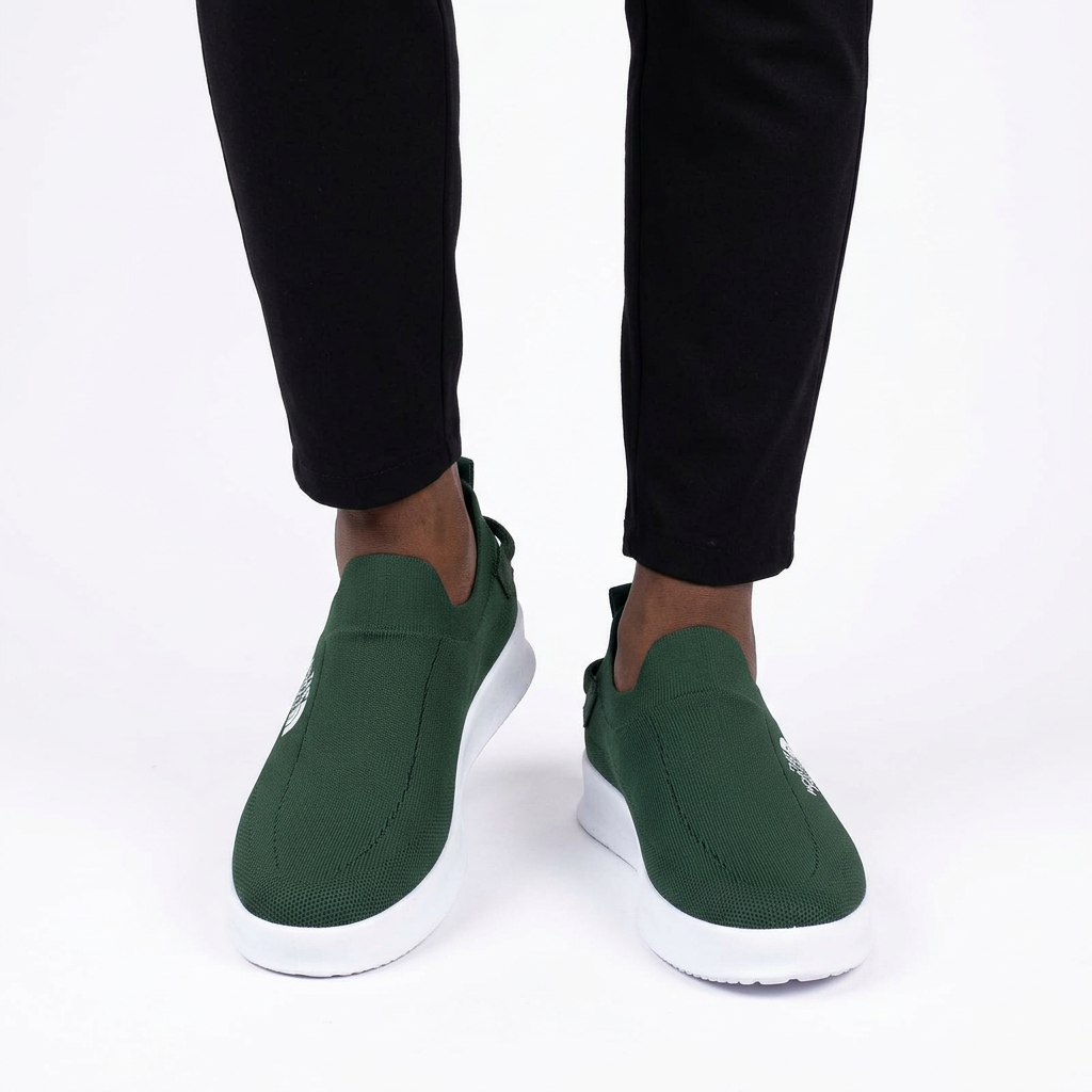 Dark green white-sole slip-on sneakers worn on both feet