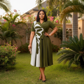 Nigerian female model wearing olive green and white abstract print pleated midi gown in upscale garden setting