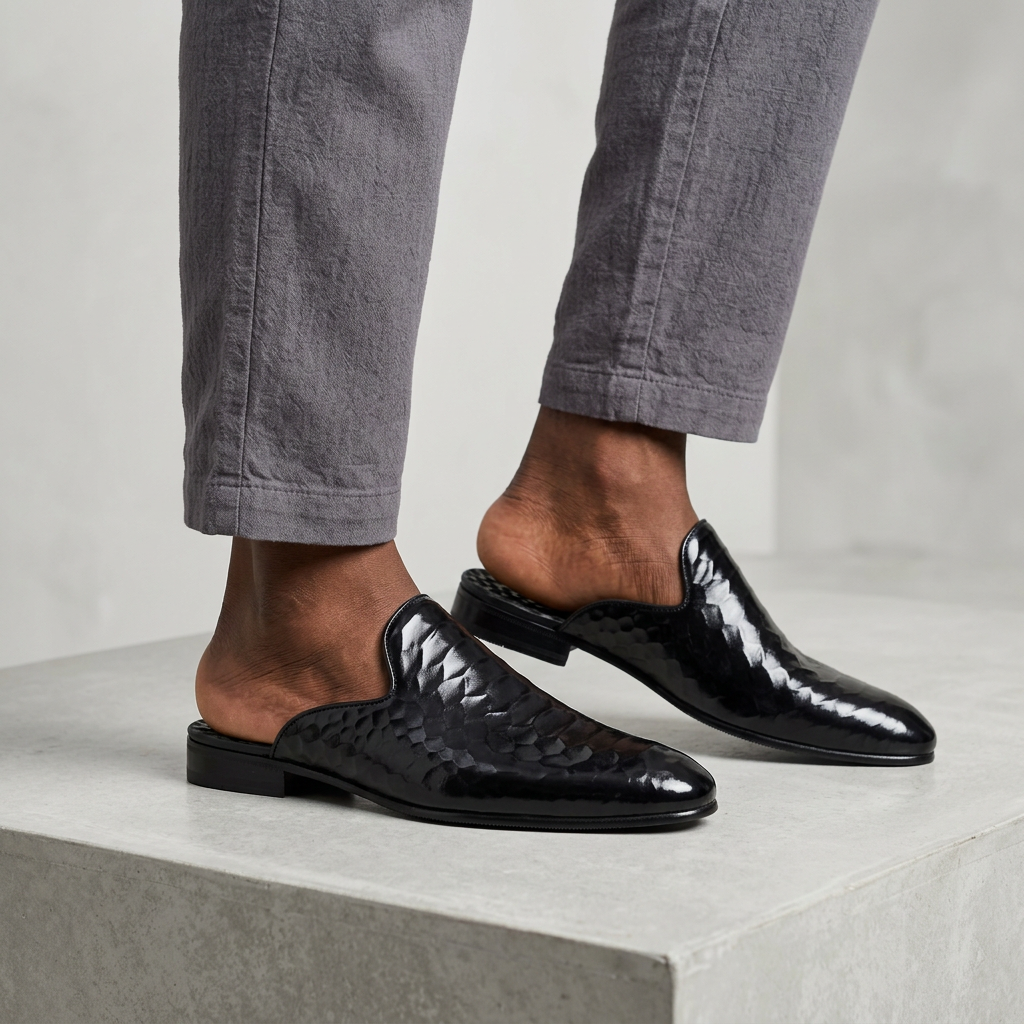 Men's black quilted-texture backless mule shoes worn with relaxed-fit trousers