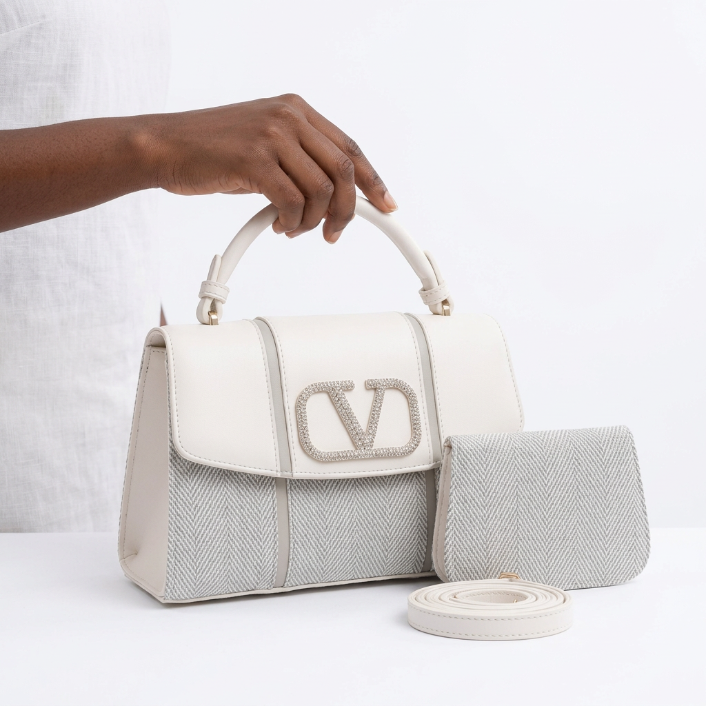 Hand holding a white and silver-grey herringbone handbag with matching pouch