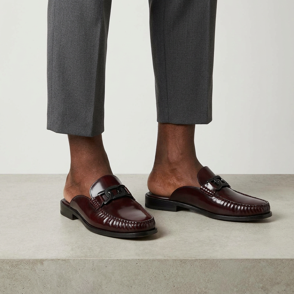 Men's burgundy buckle-detail backless mule shoes worn with relaxed-fit trousers
