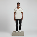 Nigerian male model wearing cream maroon gold trim football jersey on concrete plinth