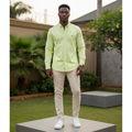 Nigerian male model wearing men's pastel lime green long-sleeve embroidered polo shirt, garden setting