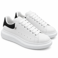 Pair of white chunky low-top sneakers with black heel panels on white background