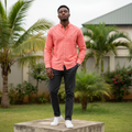 Nigerian male model wearing men's salmon pink long-sleeve button-down casual shirt, garden setting