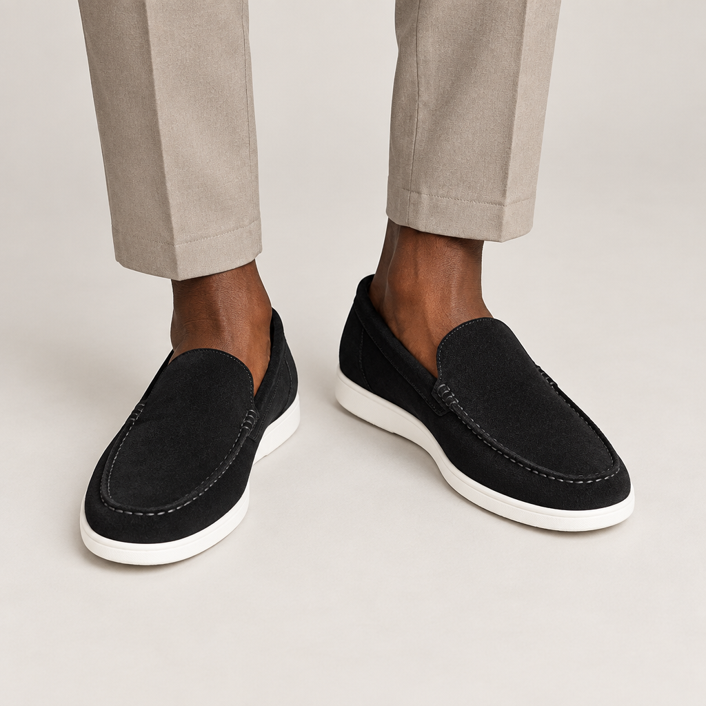 Black suede-style loafers with white soles worn with neutral trousers