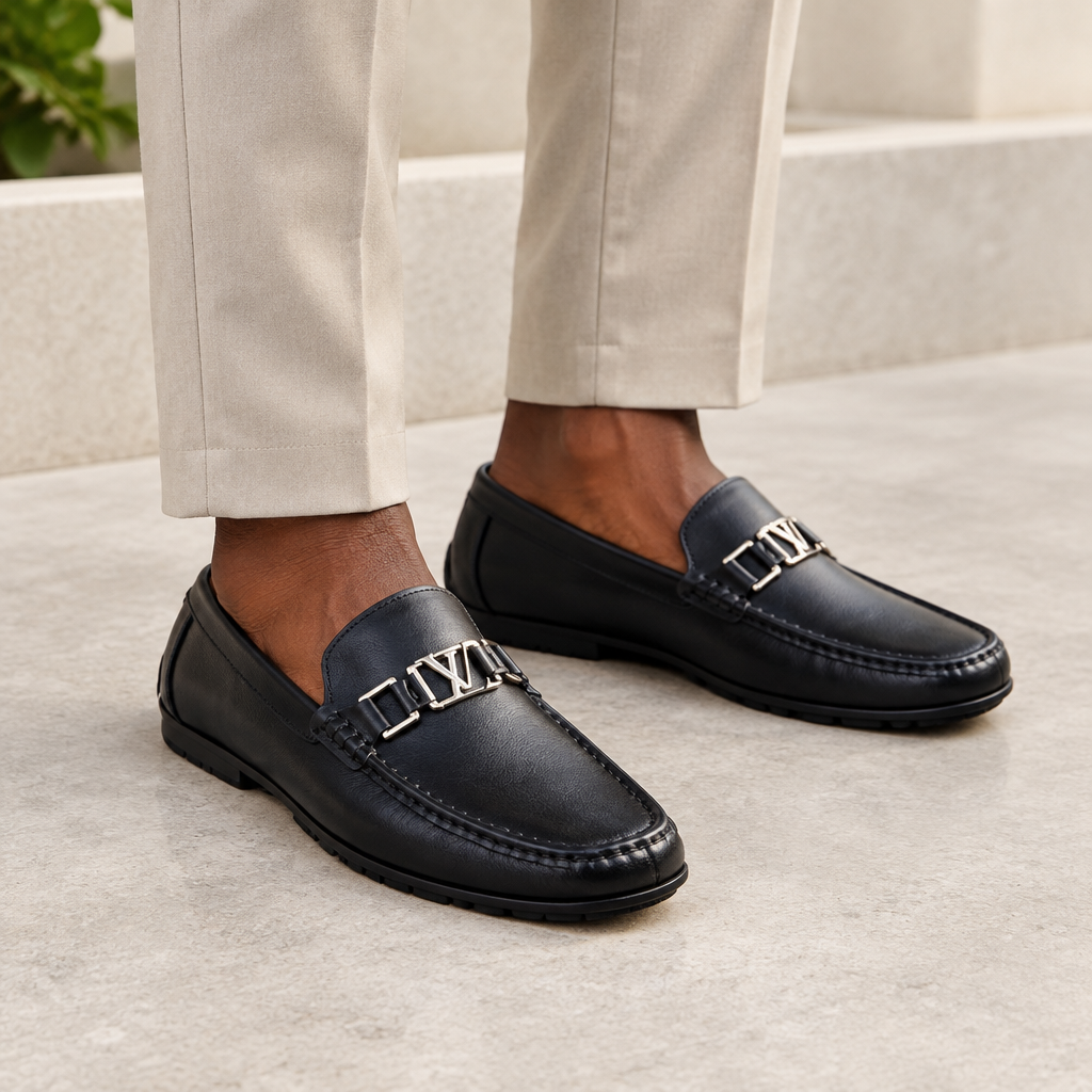 Black model wearing black men's loafers with polished metal detail