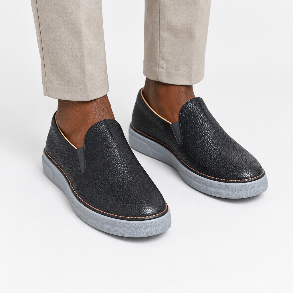 Black textured slip-on shoes with grey soles worn with neutral trousers