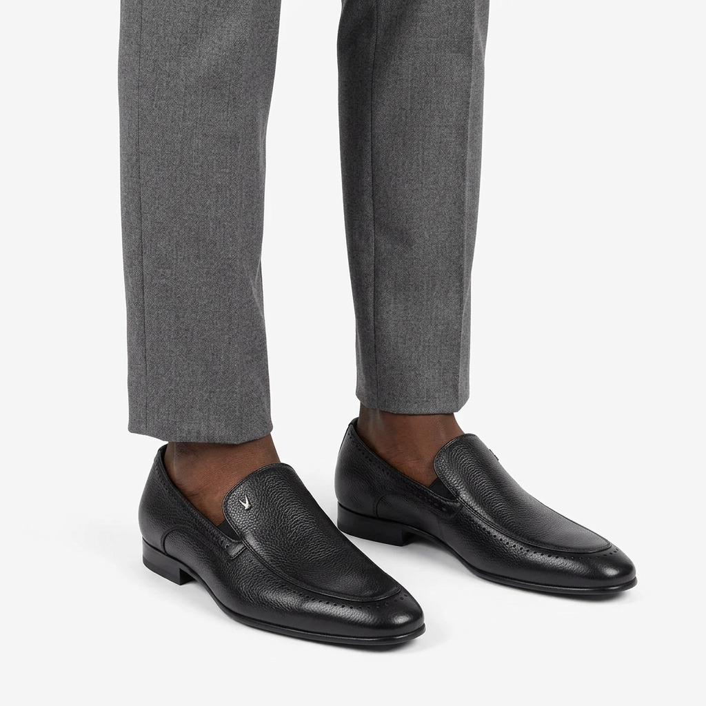 Black textured slip-on loafers properly worn on both feet