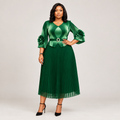 Black Nigerian model wearing an emerald pleated gown with floral cuff accents and a belted waist