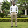 Adult Nigerian male model wearing khaki slim tapered chino trousers in garden setting