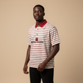 Man wearing cream and red striped polo shirt with black trousers