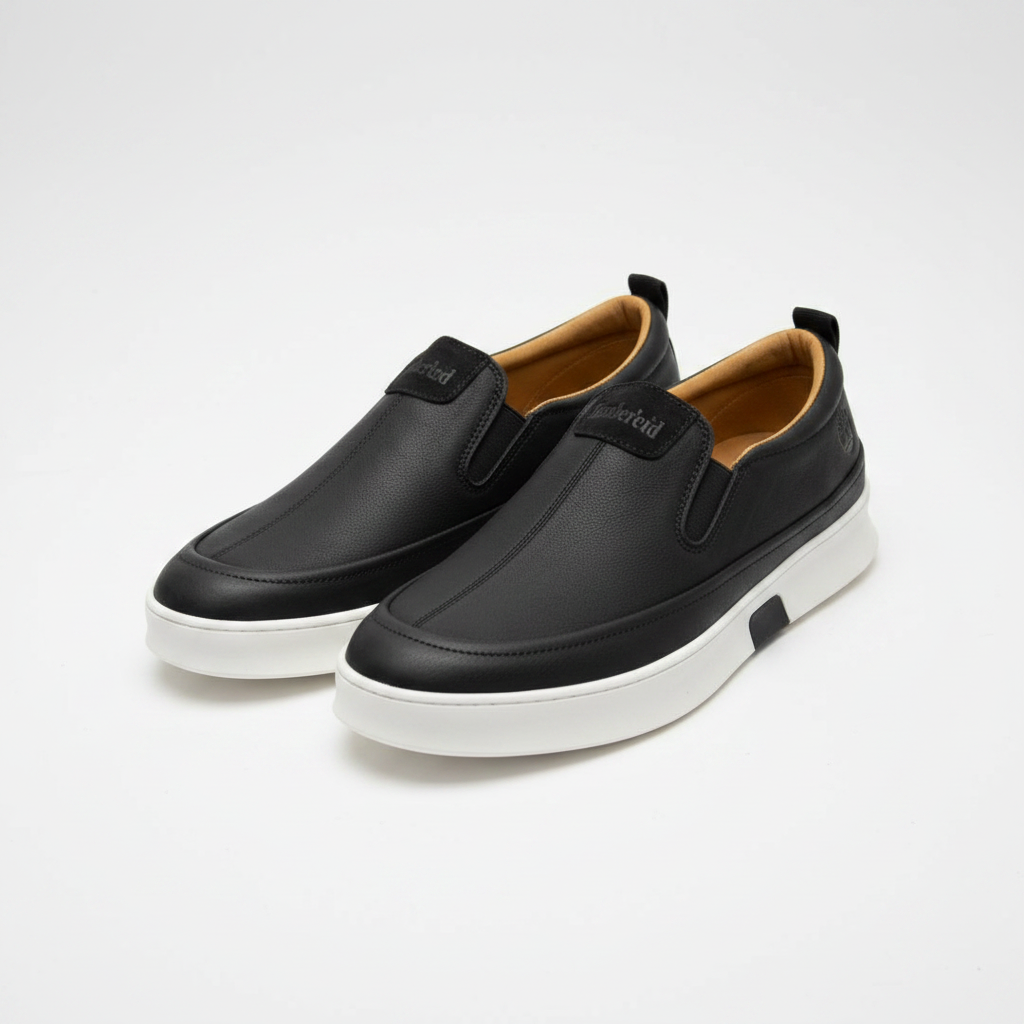 Black leather slip-on sneakers with white sole, centred on a plain off-white background