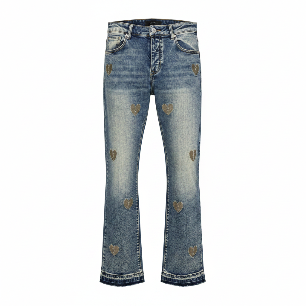 Men's vintage washed flared stacked denim jeans with scattered gold broken heart embroidery patches and raw frayed hem, ghost mannequin front view
