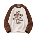 Cream knit sweater with brown raglan sleeves and a brown slogan graphic