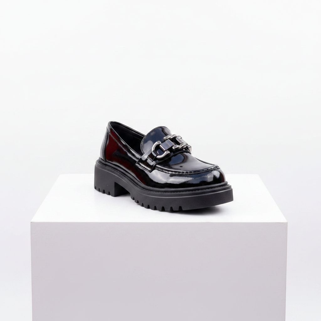 Black patent leather chunky platform loafer on white platform – studio shot