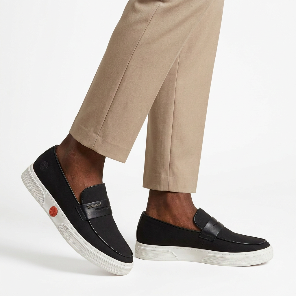 Both black white-sole loafers worn by a Nigerian male model on a white studio background